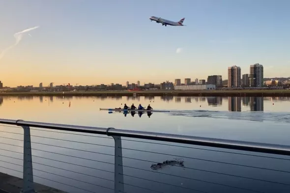 Rowers on the Thames with the sunset and a plane flying over head